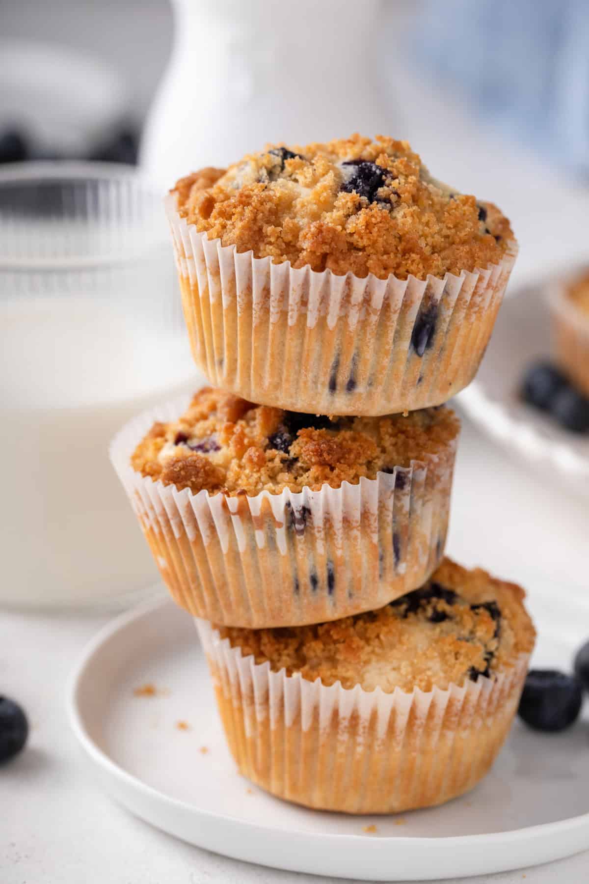 Three bisquick blueberry muffins stacked on a white plate.