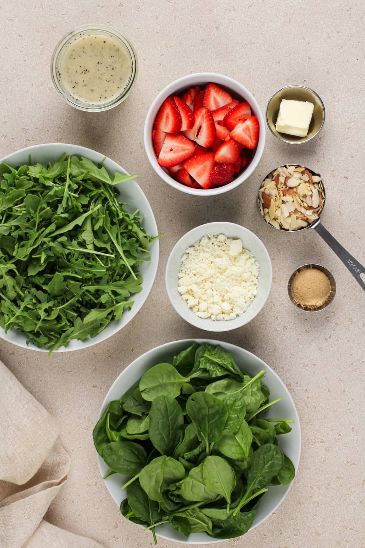 Strawberry salad ingredients arranged on a beige countertop.