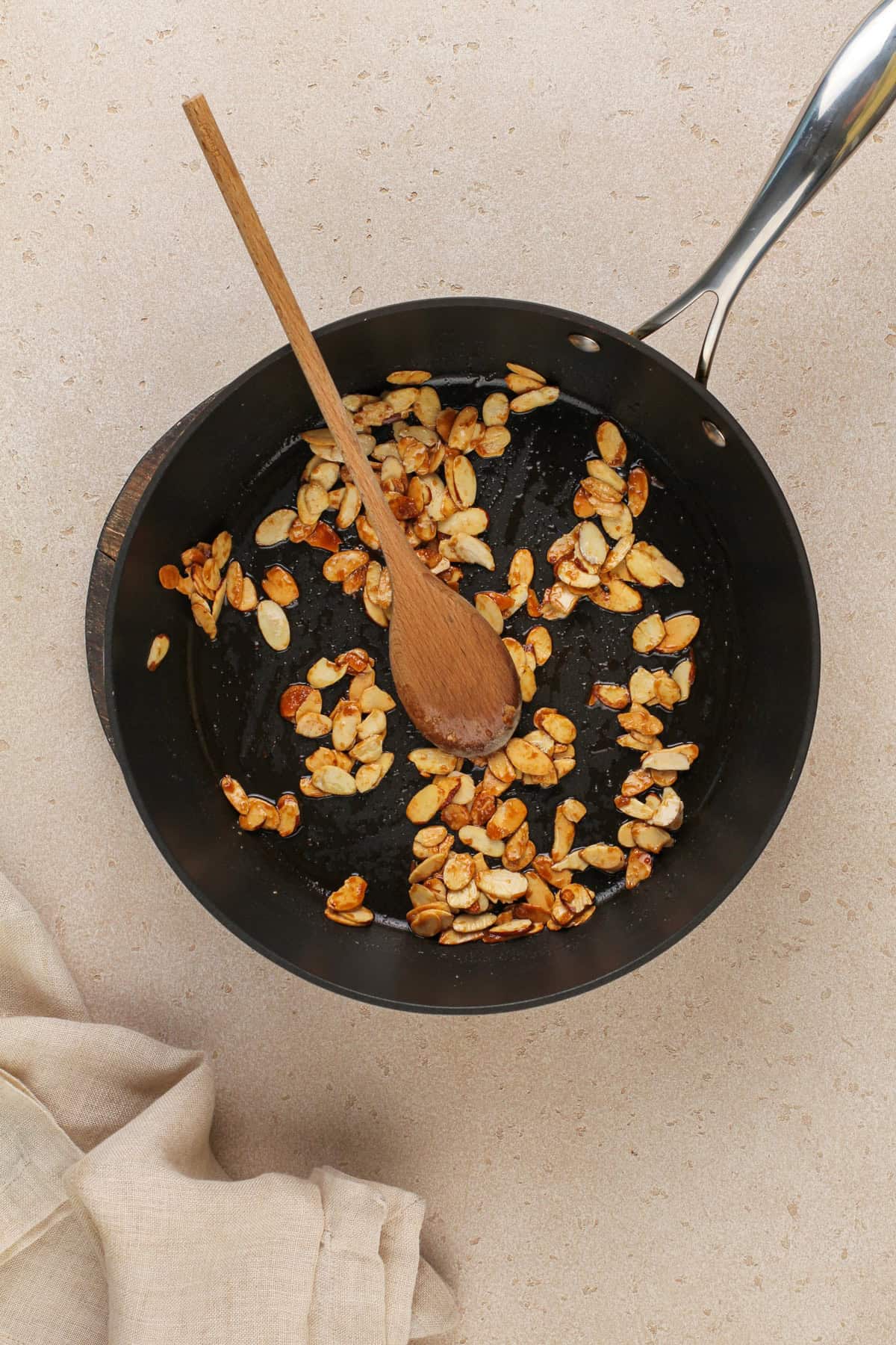 Almonds being caramelized in a nonstick pan.