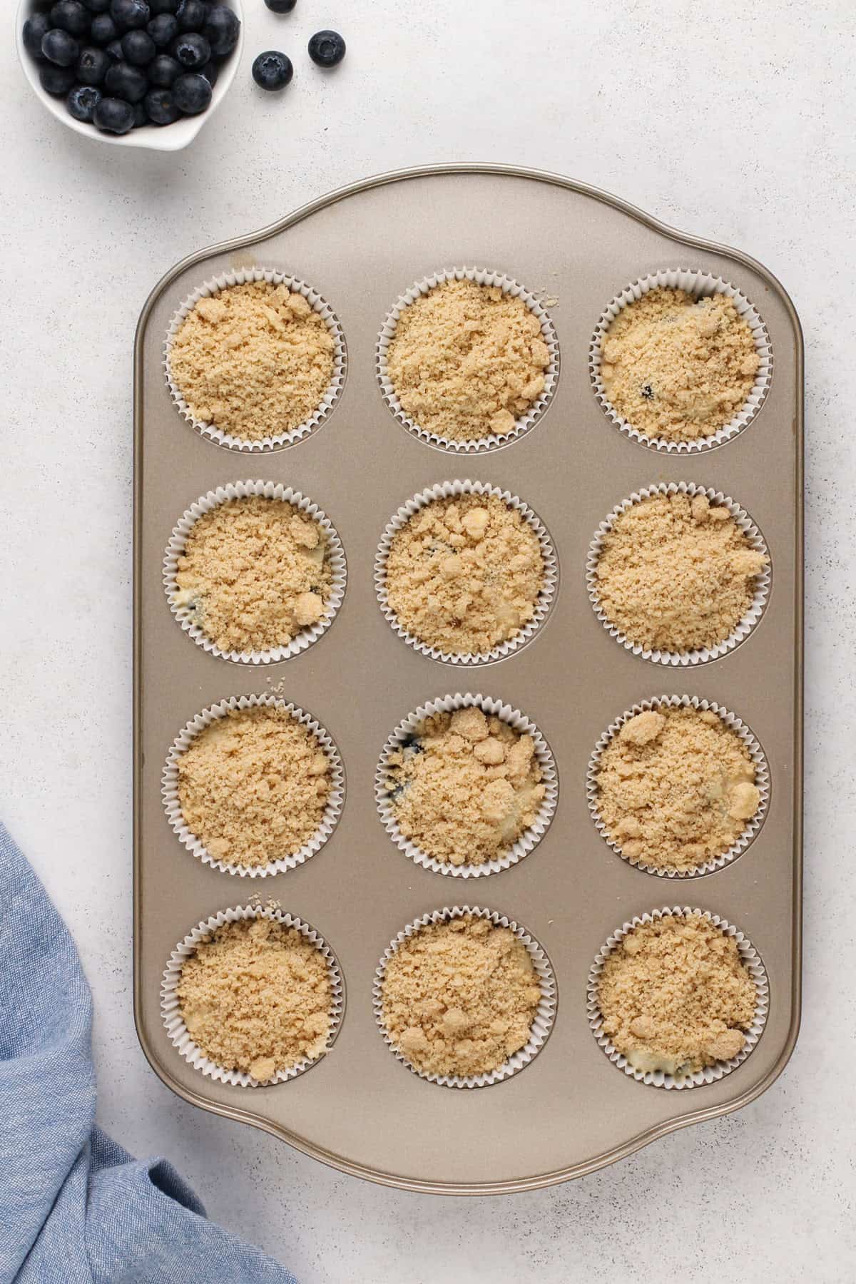 Unbaked bisquick blueberry muffins in a muffin tin, ready to go in the oven.