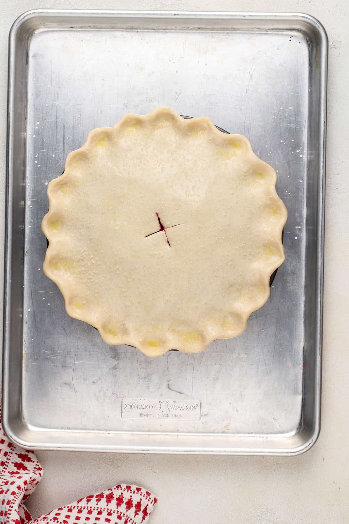 Unbaked sour cherry pie on a baking sheet, ready to go in the oven.