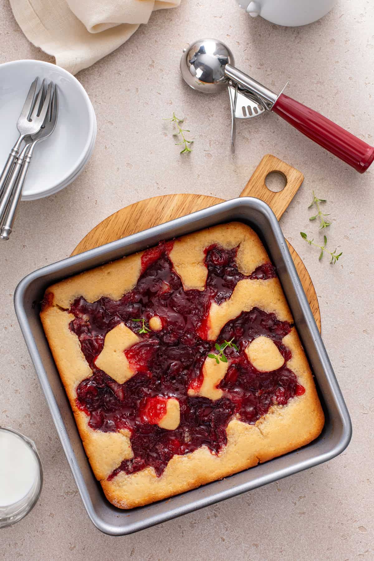 Overhead view of a pan of baked easy cherry cobbler on a wooden trivet.