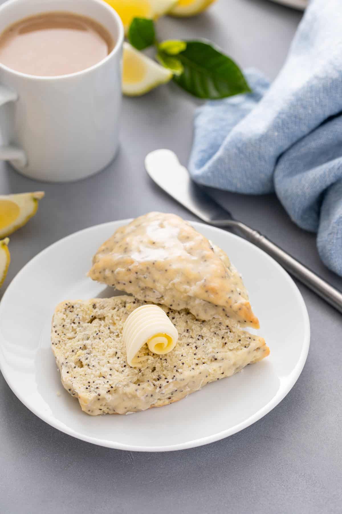 Lemon poppy seed scone sliced in half with a pat of butter on it.
