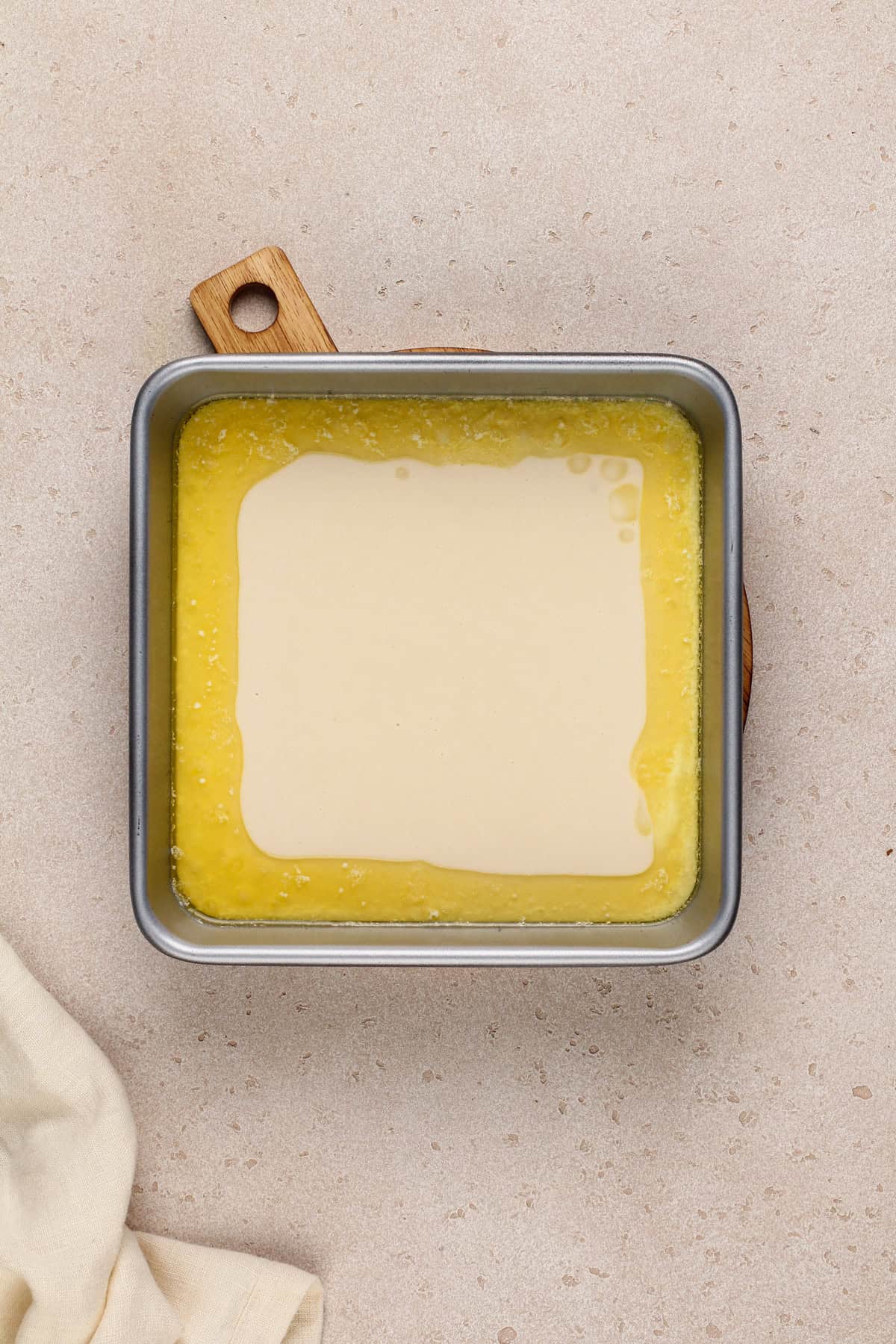 Cobbler batter and melted butter in a metal baking pan.