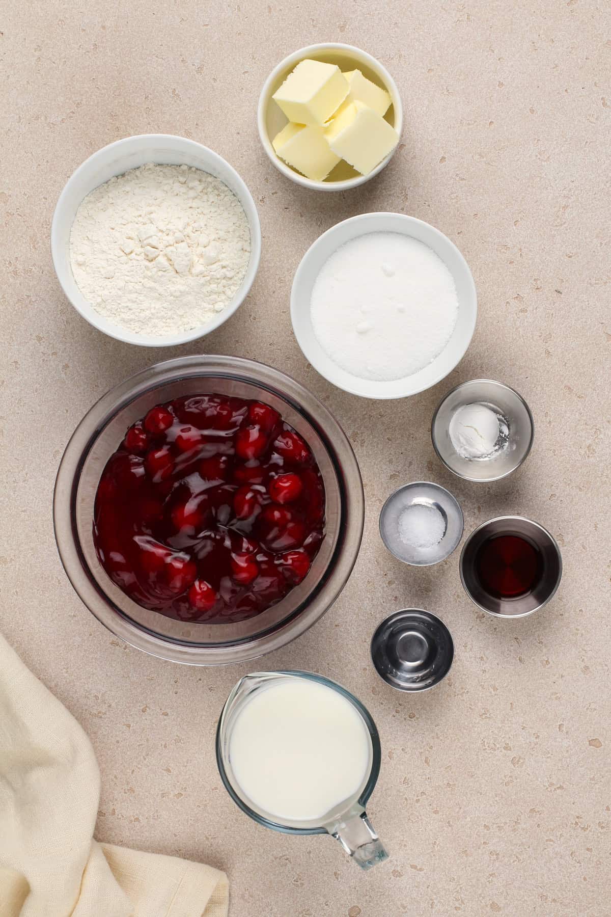 Ingredients for easy cherry cobbler arranged on a beige countertop.