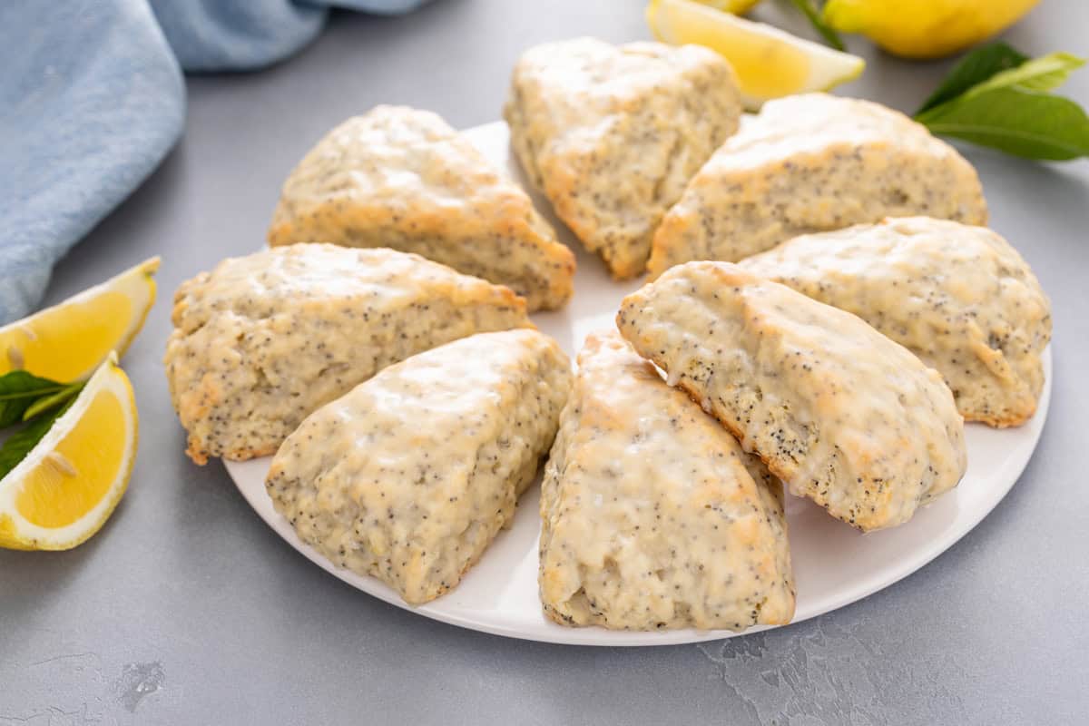 Lemon poppy seed scones arranged in a circle on a white plate.