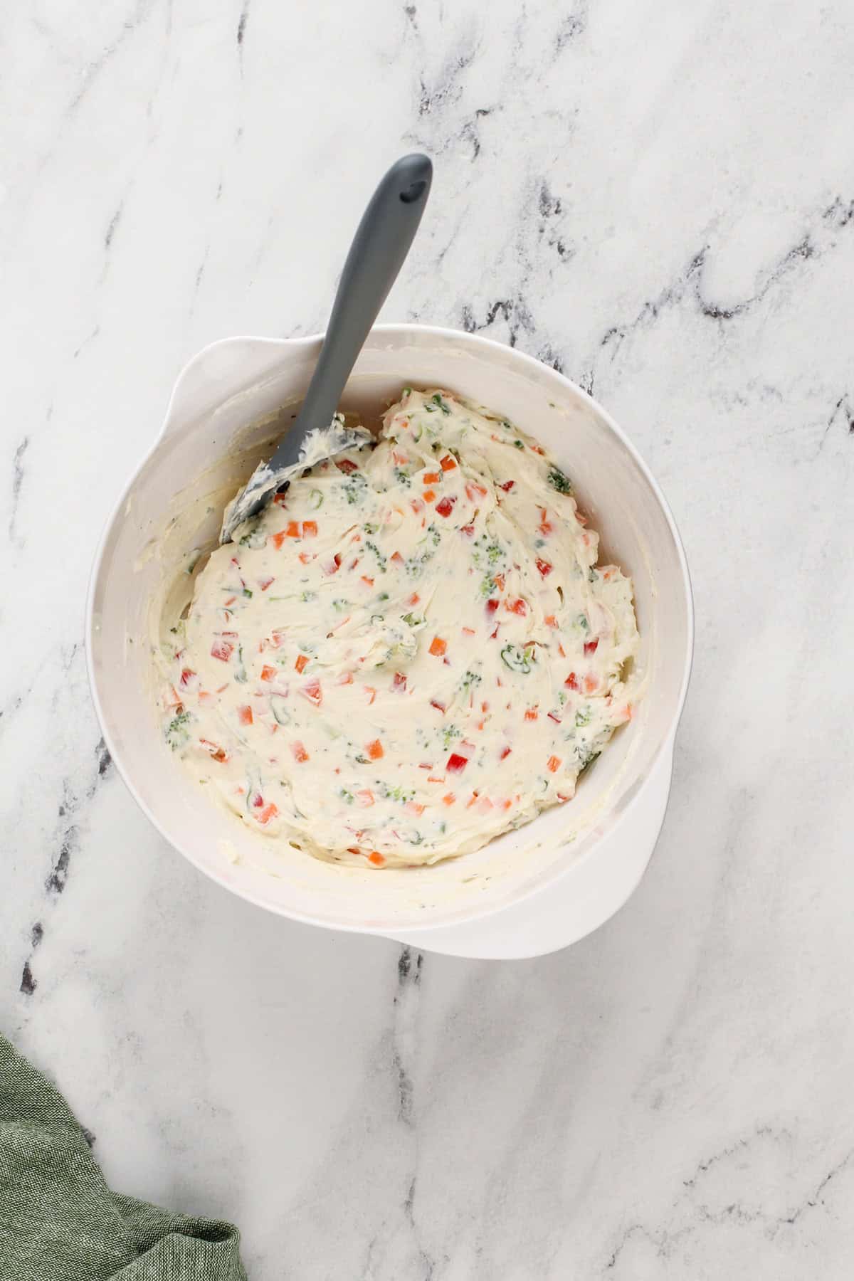 Veggie cream cheese mixed in a white mixing bowl.