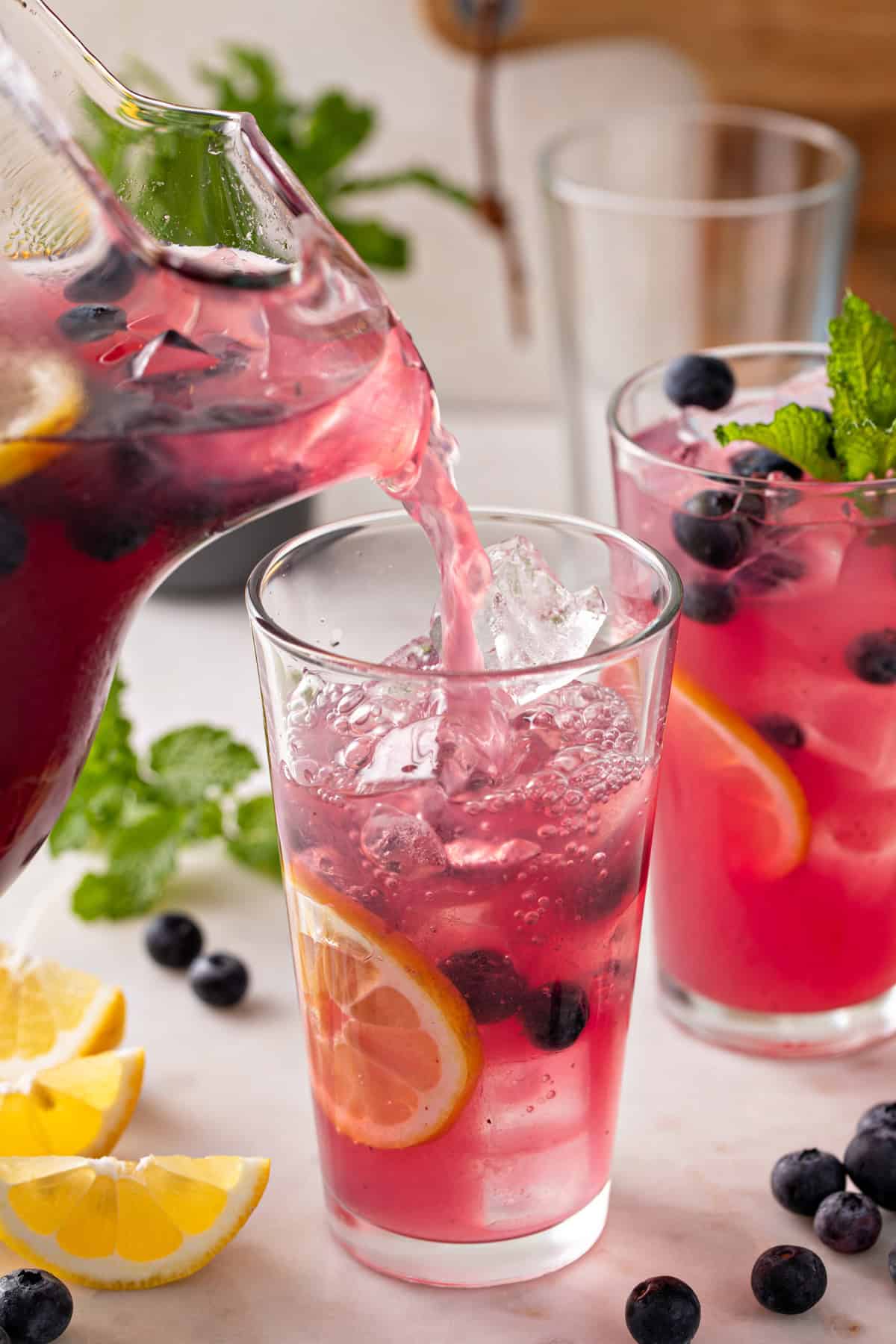 Blueberry lemonade being poured into a glass.