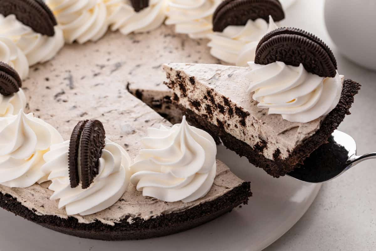 Pie server lifting up a slice of oreo pie from a serving platter.