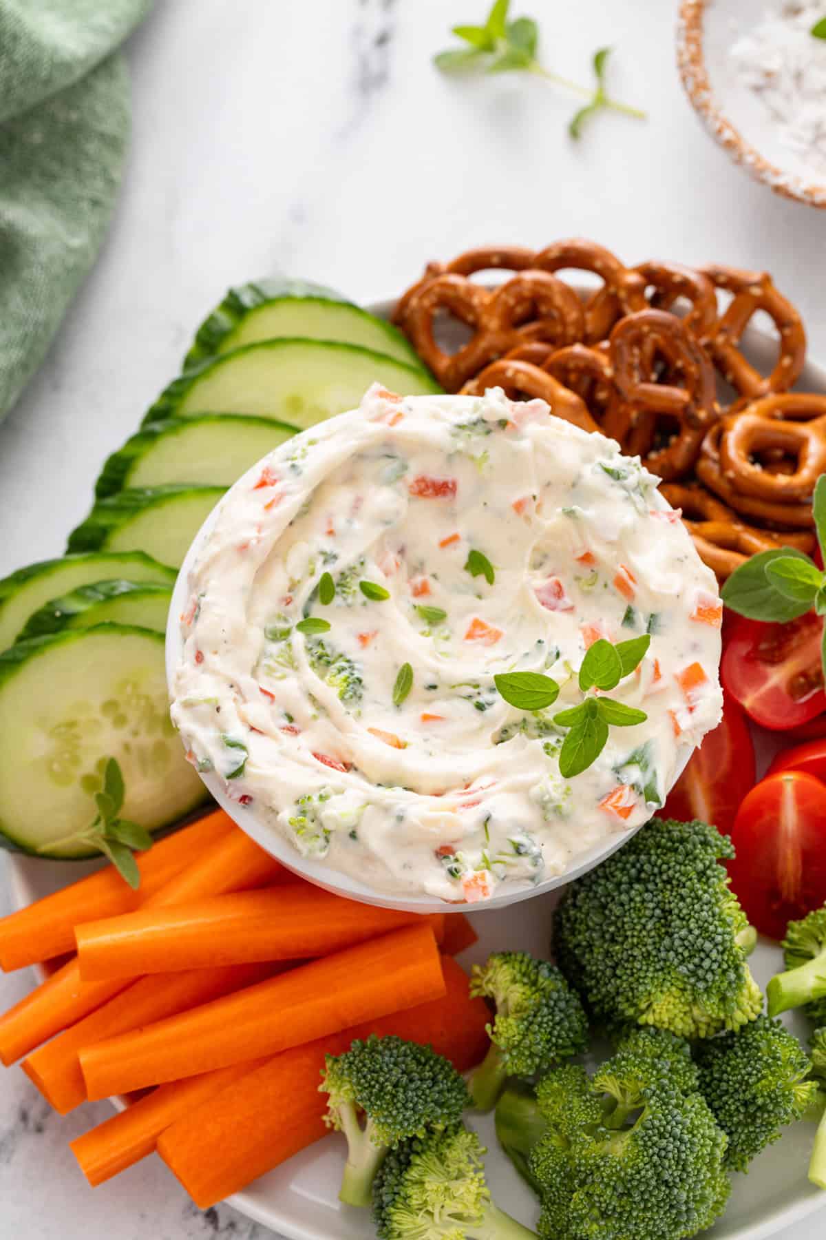 Bowl of veggie cream cheese in the middle of a platter of crudites and pretzel twists.