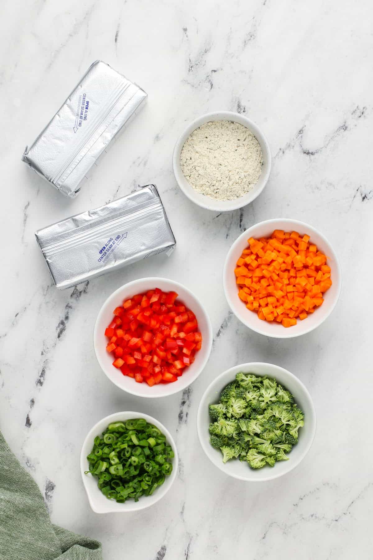 Ingredients for veggie cream cheese arranged on a marble countertop.