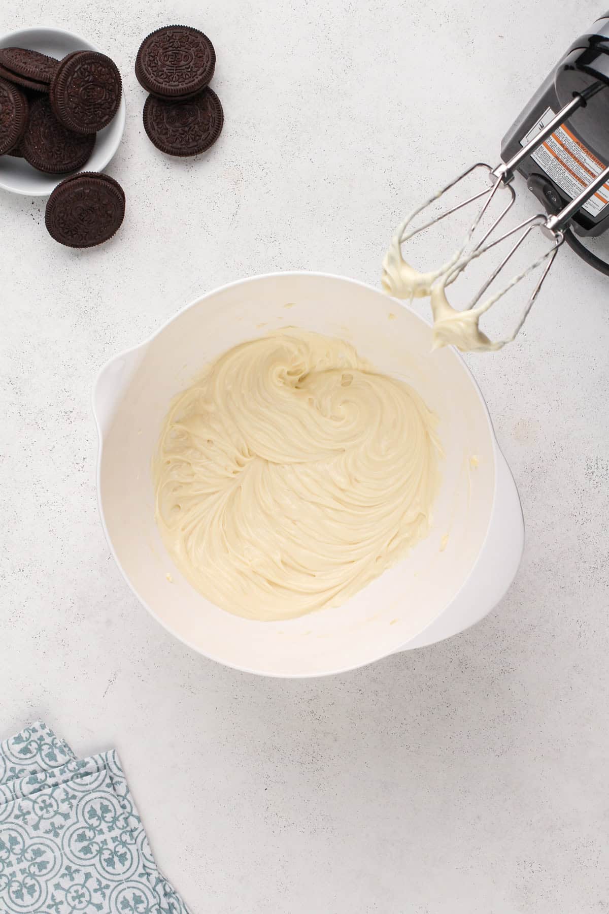 Cream cheese beaten with sugar and vanilla in a white bowl.