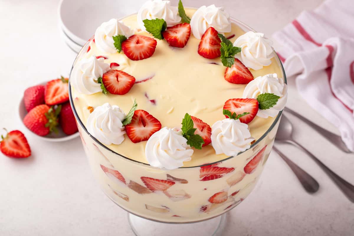 Strawberry trifle in a trifle dish topped with whipped cream and fresh strawberries.