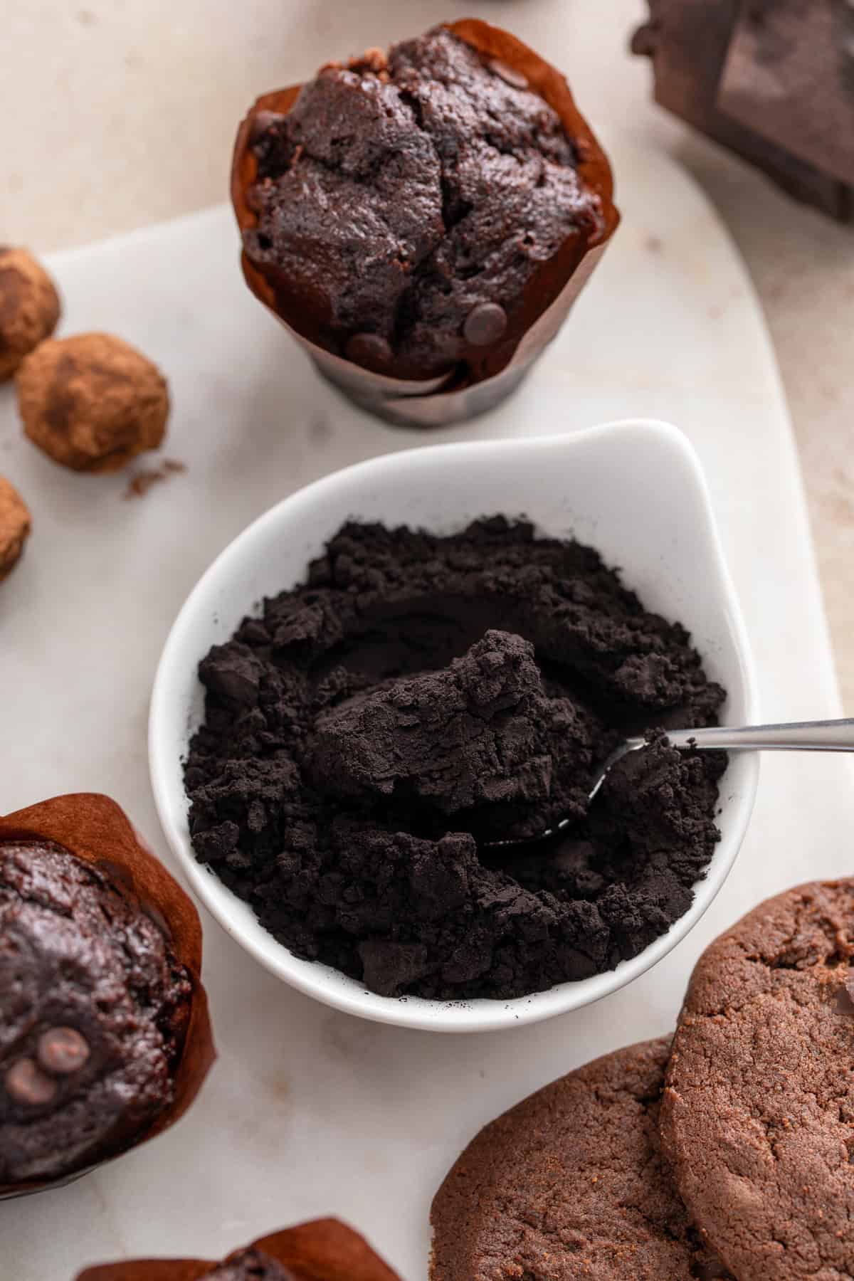 Bowl of black cocoa powder with a spoon in it.