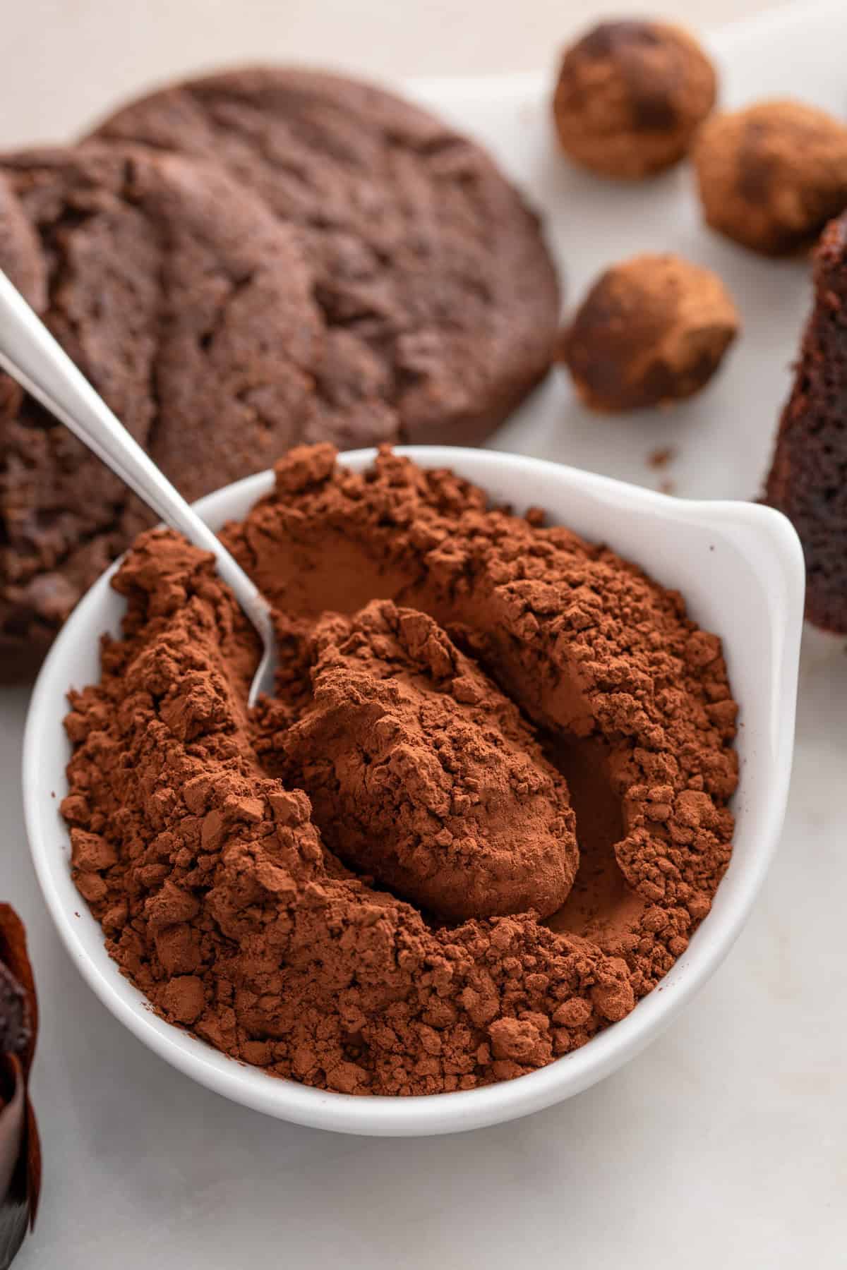 Bowl of dutched cocoa powder with a spoon in it.