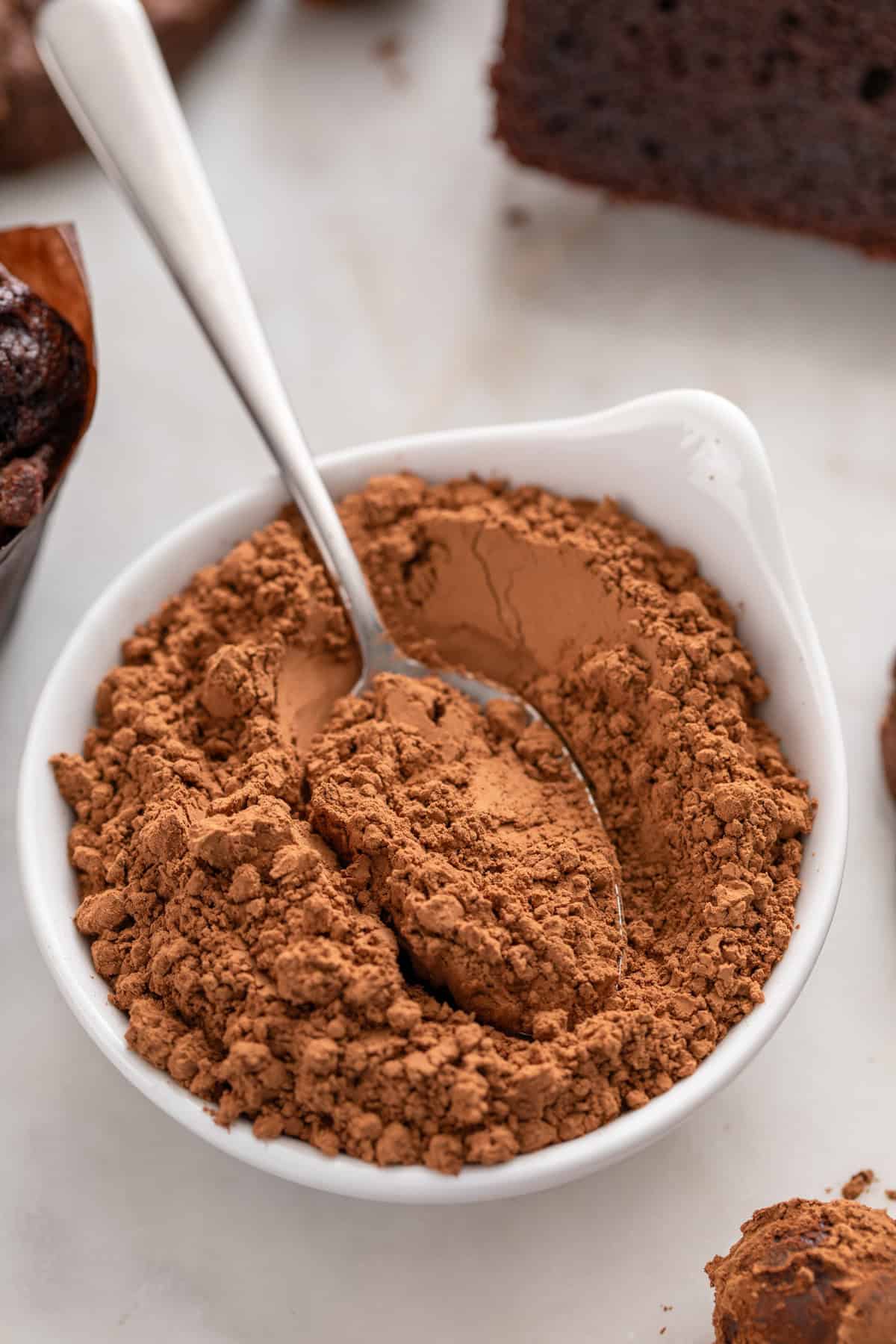 Bowl of natural cocoa powder with a spoon in it.