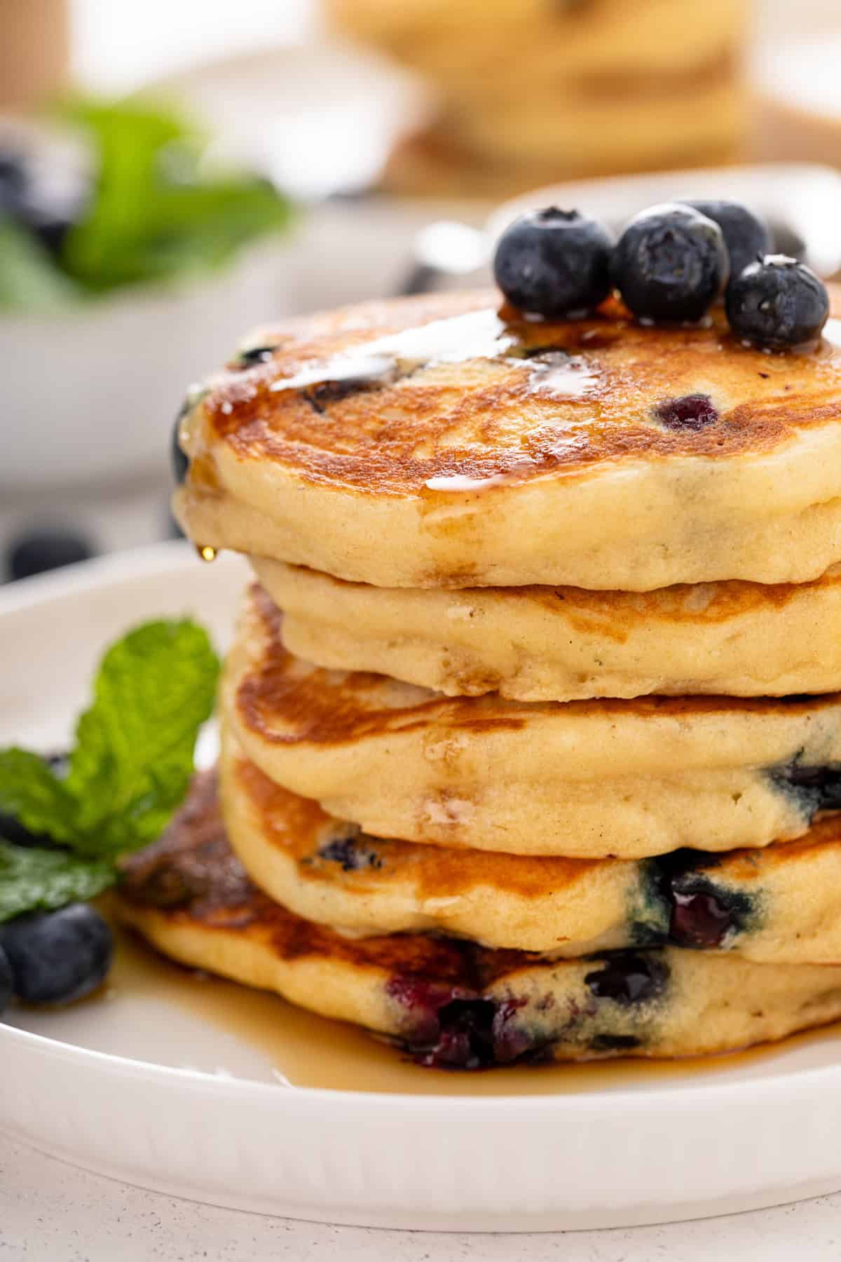 Close up of a stack of blueberry pancakes with syrup on them.