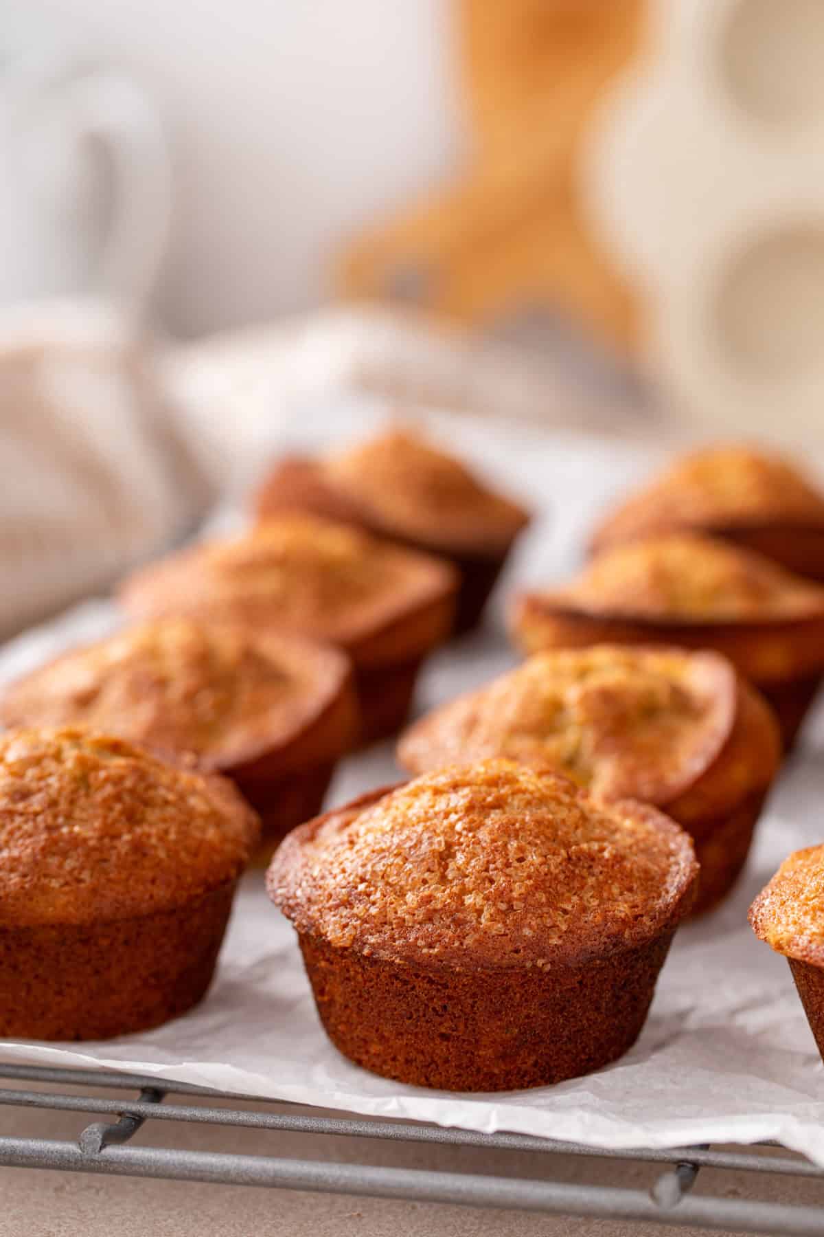 Banana bread muffins cooling on a piece of parchment paper.