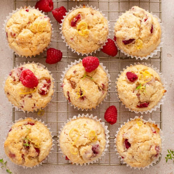 Nine lemon raspberry muffins lined up on a wire rack.