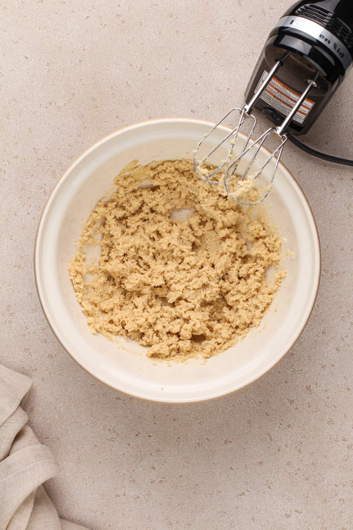 Butter and sugar creamed together in a ceramic mixing bowl.