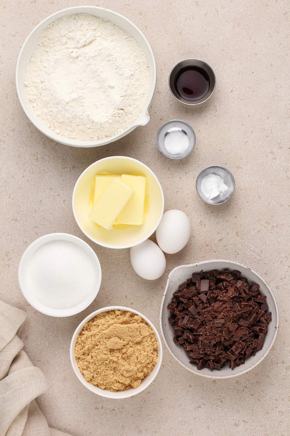Ingredients for easy chocolate chip cookies arranged on a beige countertop.