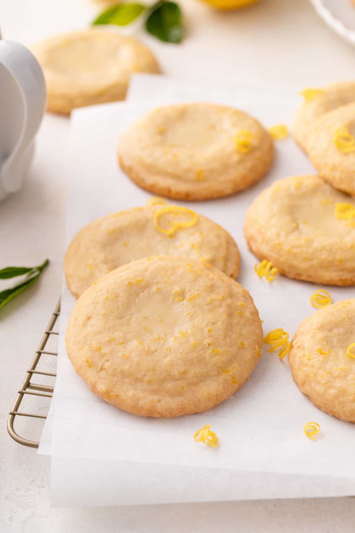 Glazed lemon cookies scattered on a piece of parchment paper.