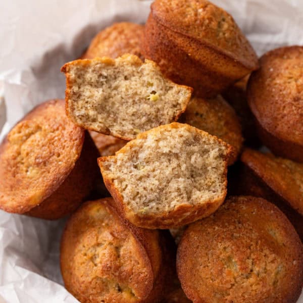 Halved banana bread muffin resting on top of full muffins.