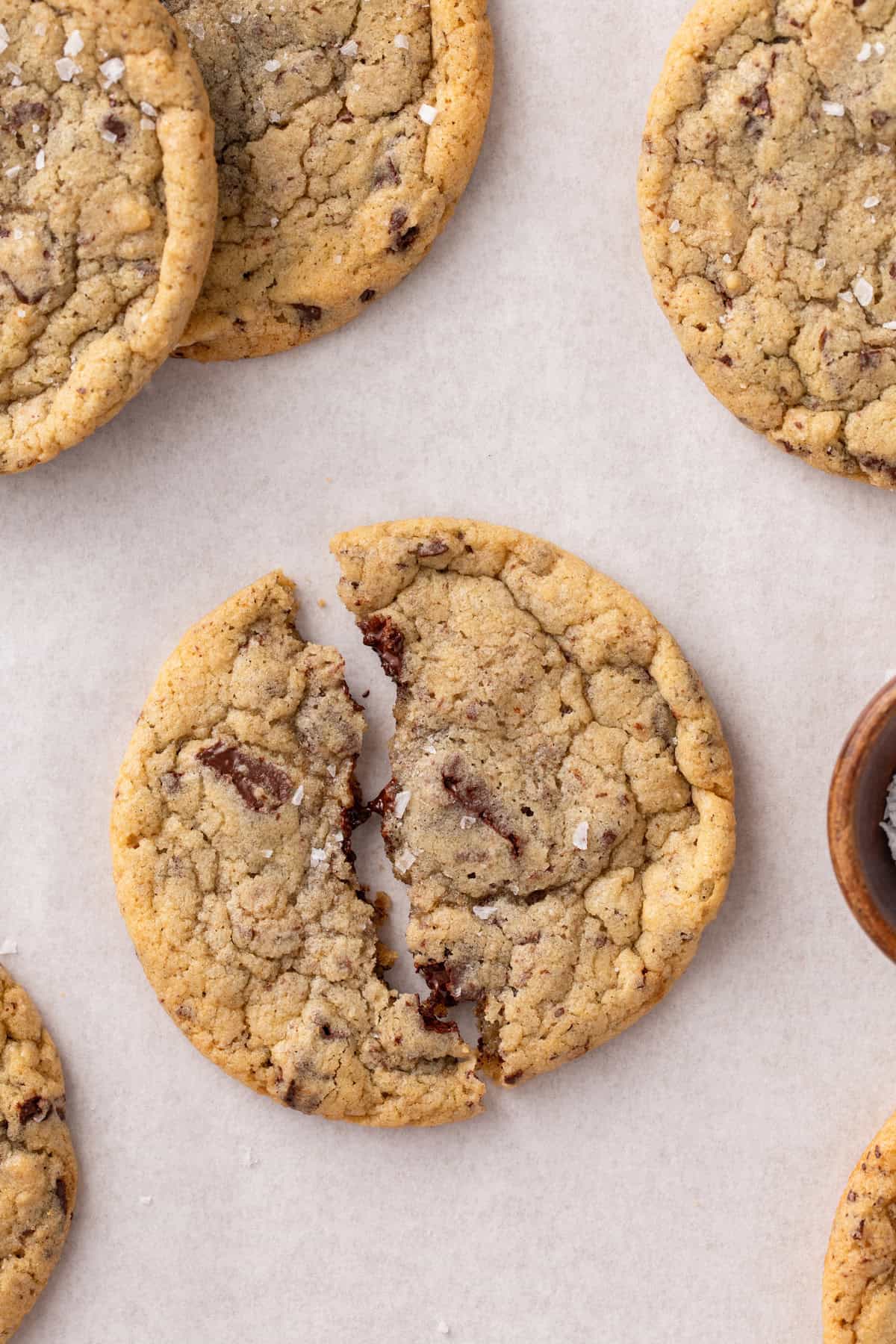 Easy chocolate chip cookie broken in half on a piece of parchment paper.