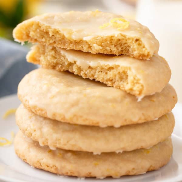 Halved glazed lemon cookie on a stack of cookies.