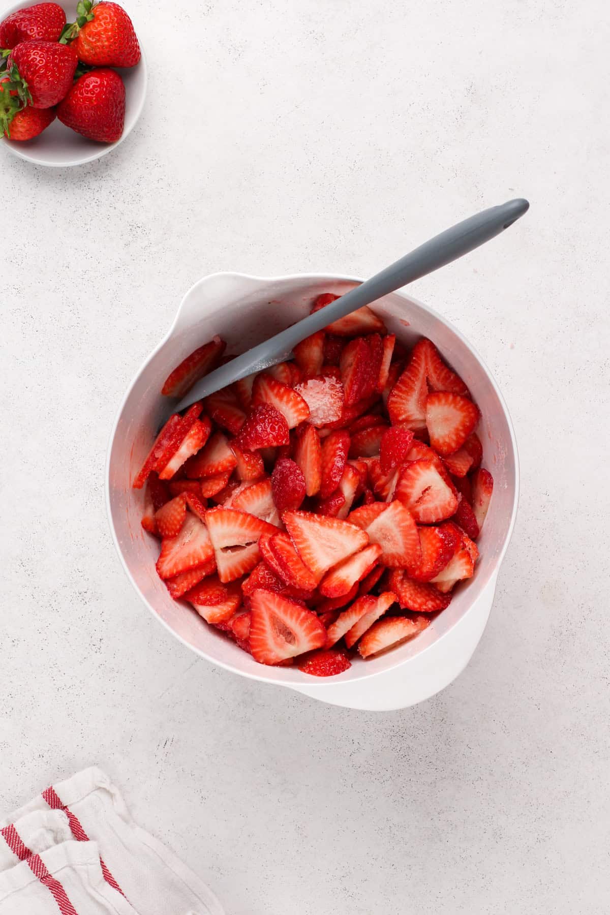 Sliced strawberries in a white bowl.