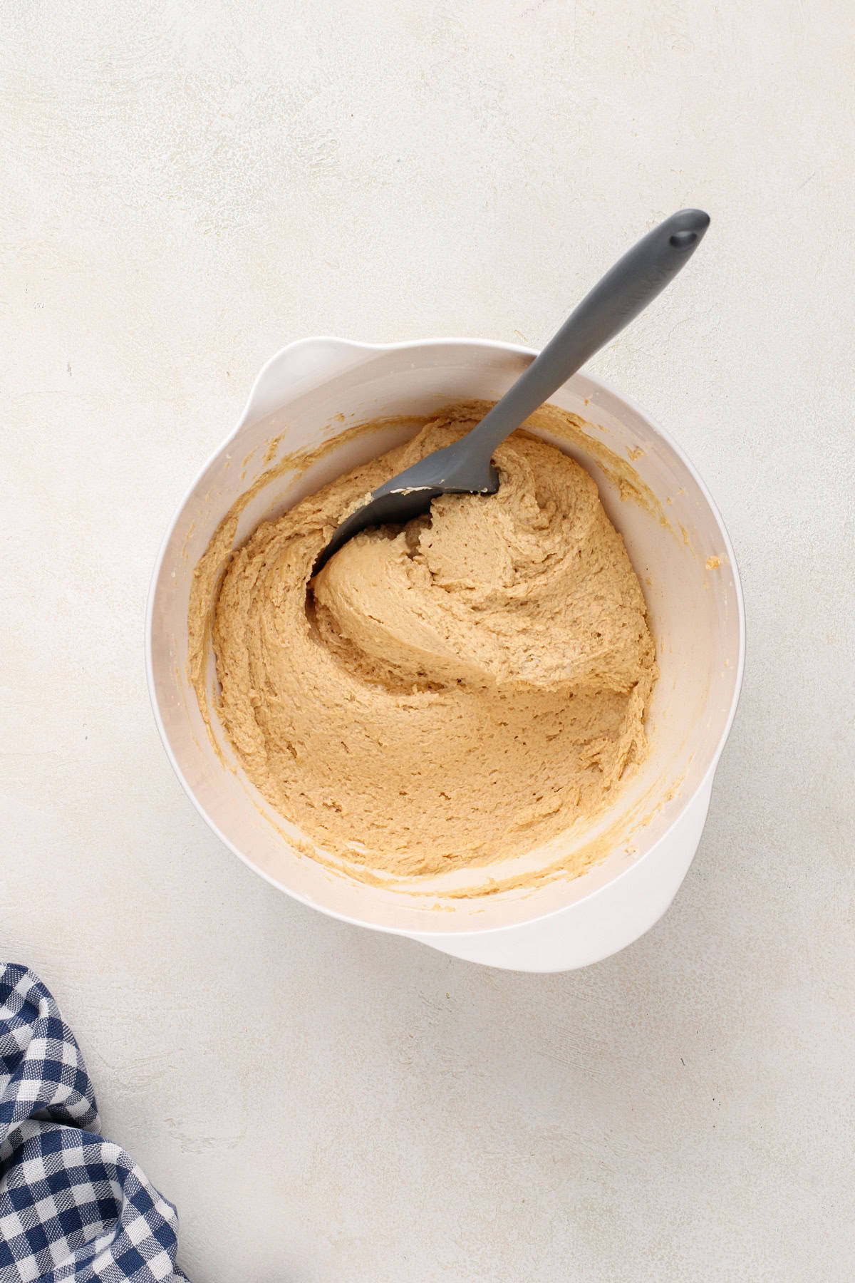 Marshmallow creme folded into peanut butter dip in a white bowl.