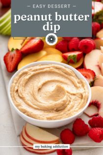 White bowl of peanut butter dip set on a platter of fresh fruit. Text overlay includes recipe name.