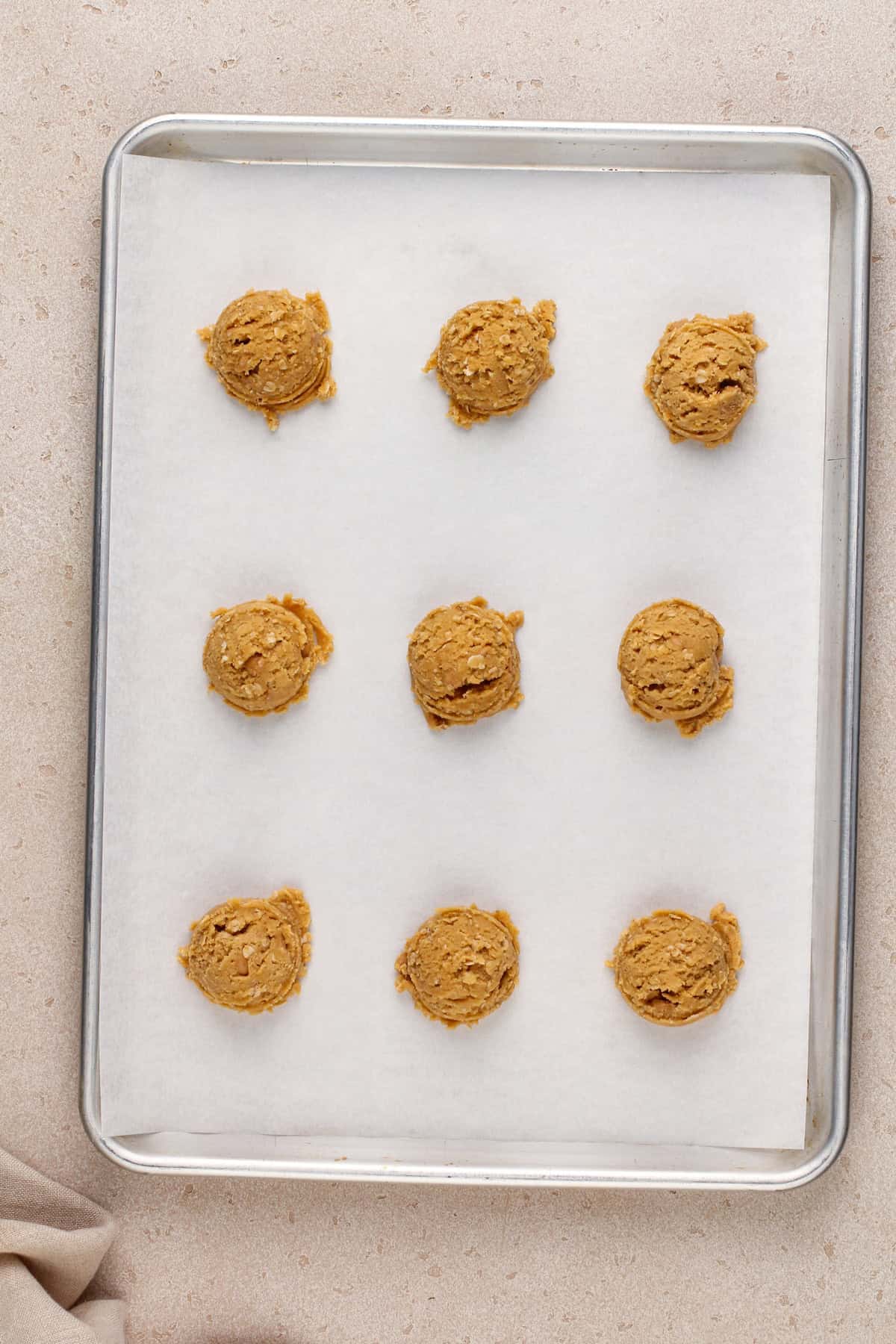 Scoops of peanut butter oatmeal cookie dough on a parchment-lined baking sheet.