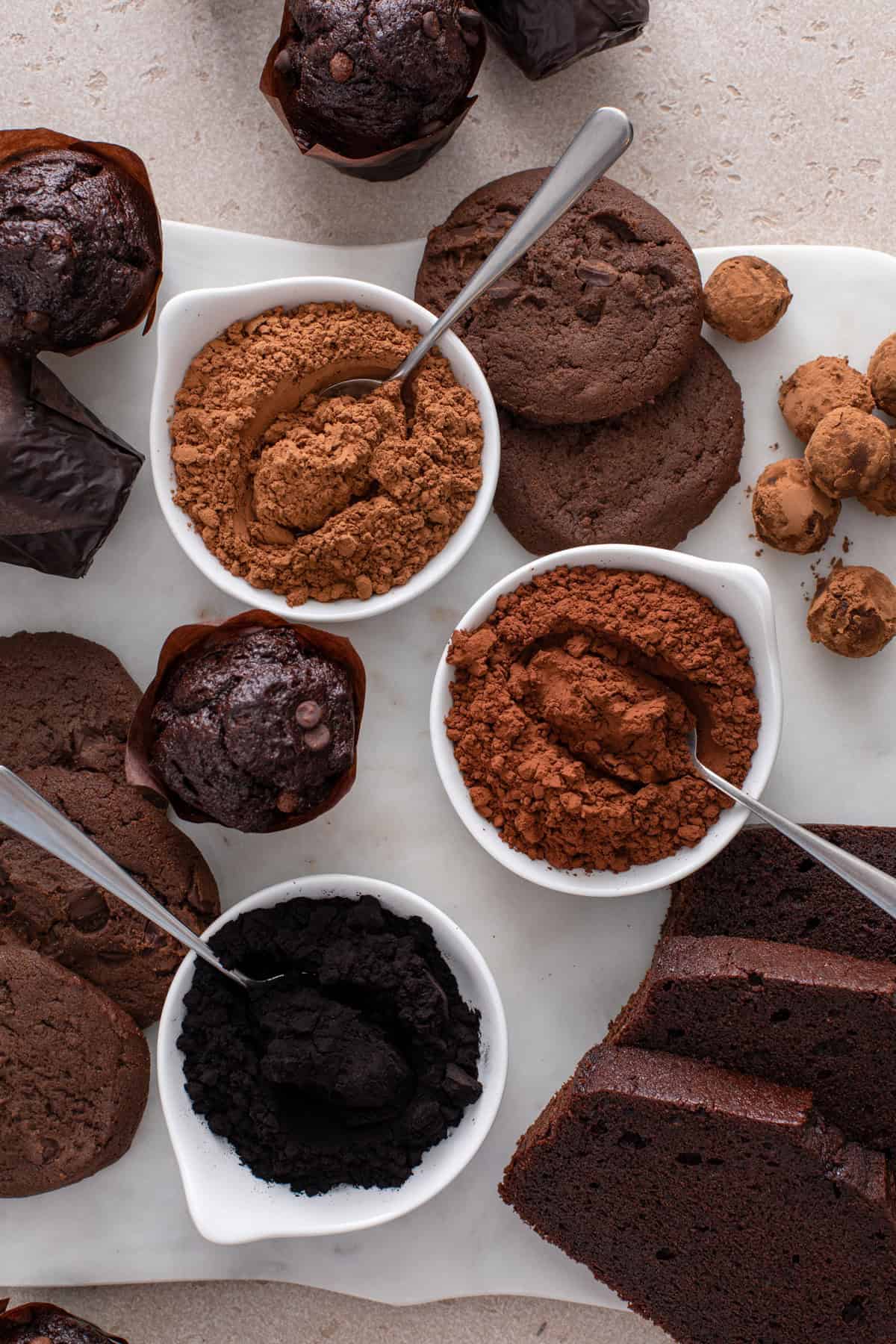 Overhead view of three bowls. From the top down, they hold: natural cocoa powder, dutched cocoa, and black cocoa.