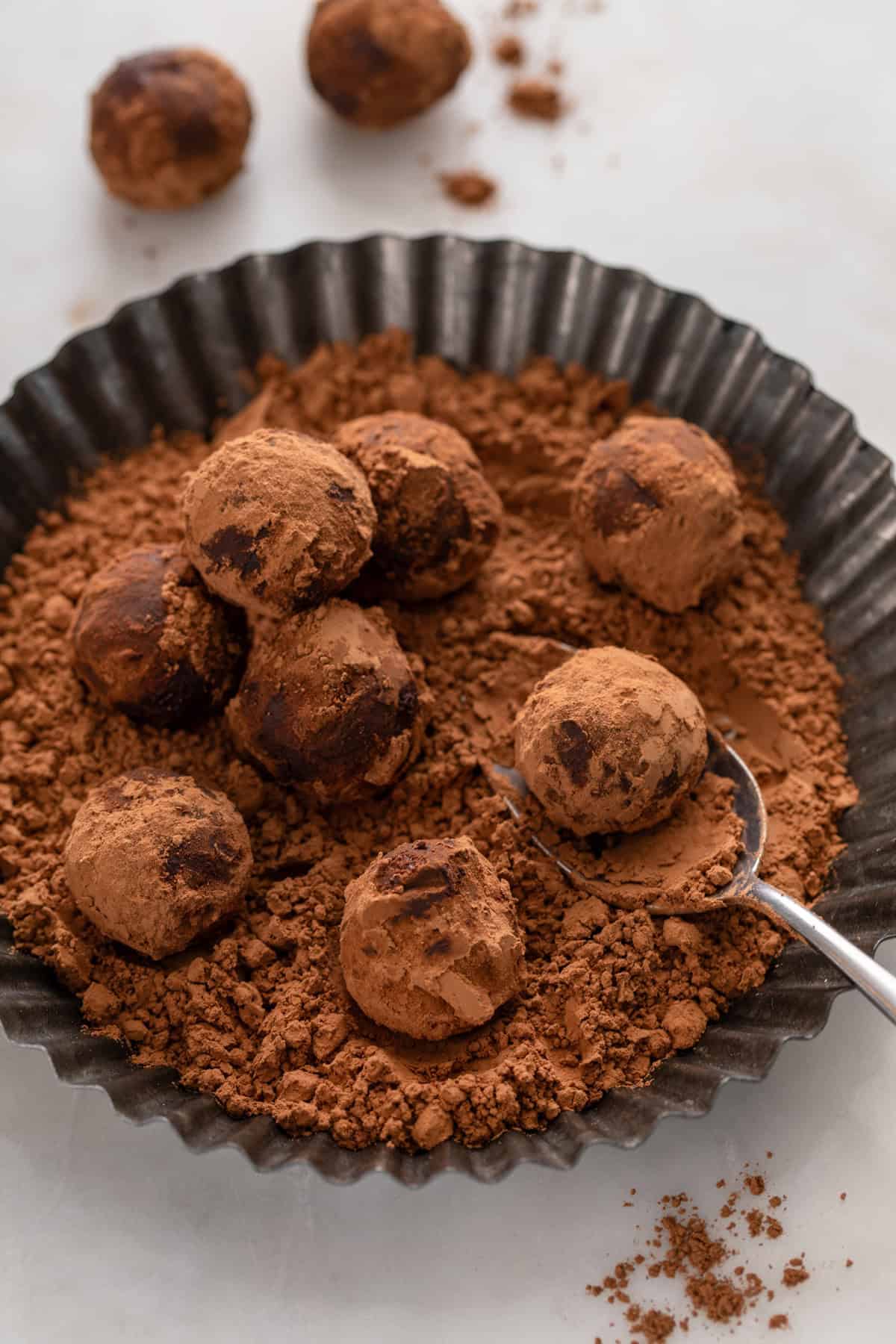 Homemade truffles being rolled in cocoa powder.