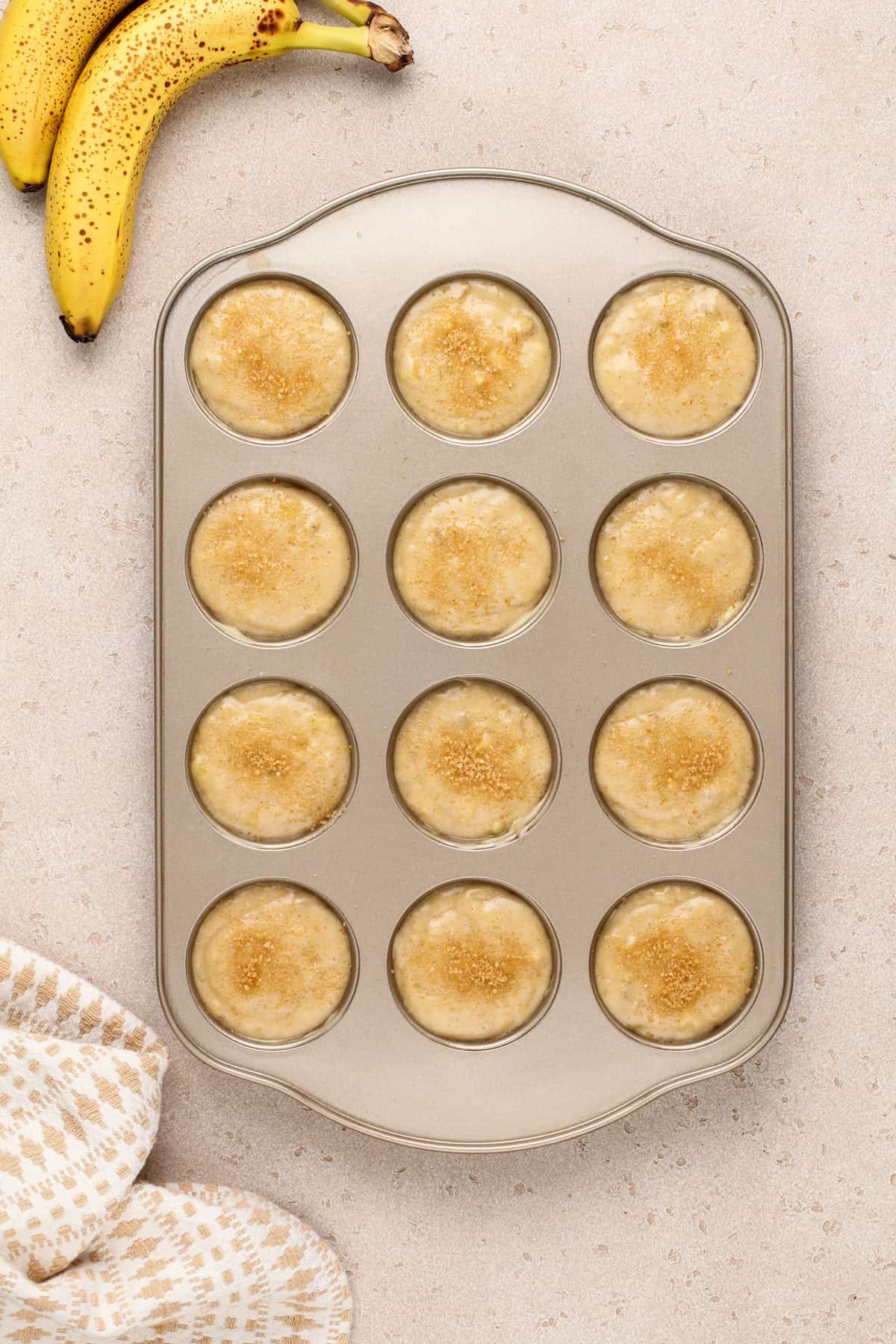 Unbaked banana bread muffins in a muffin tin, ready to go in the oven.