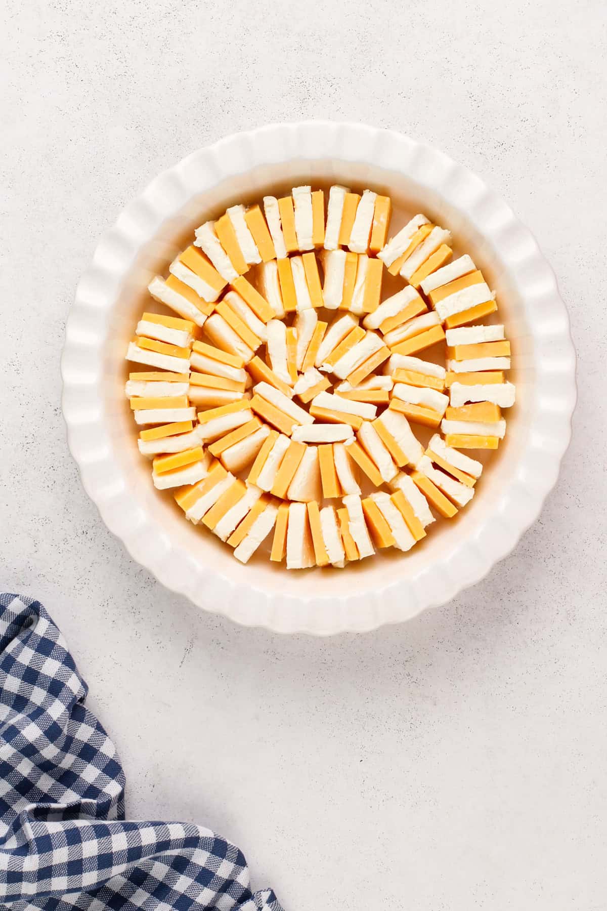 Cheddar and cream cheese blocks arranged in a deep dish pie plate.