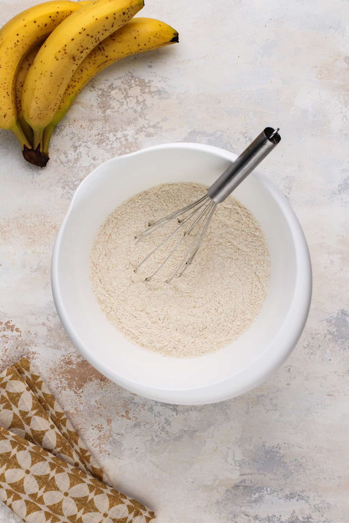 Dry ingredients for banana bread whisked together in a white bowl.