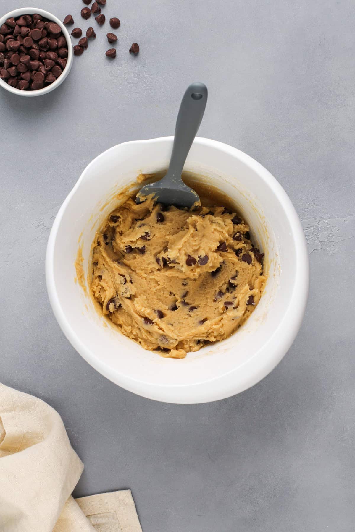 Chocolate chip cookie bar dough in a white mixing bowl.