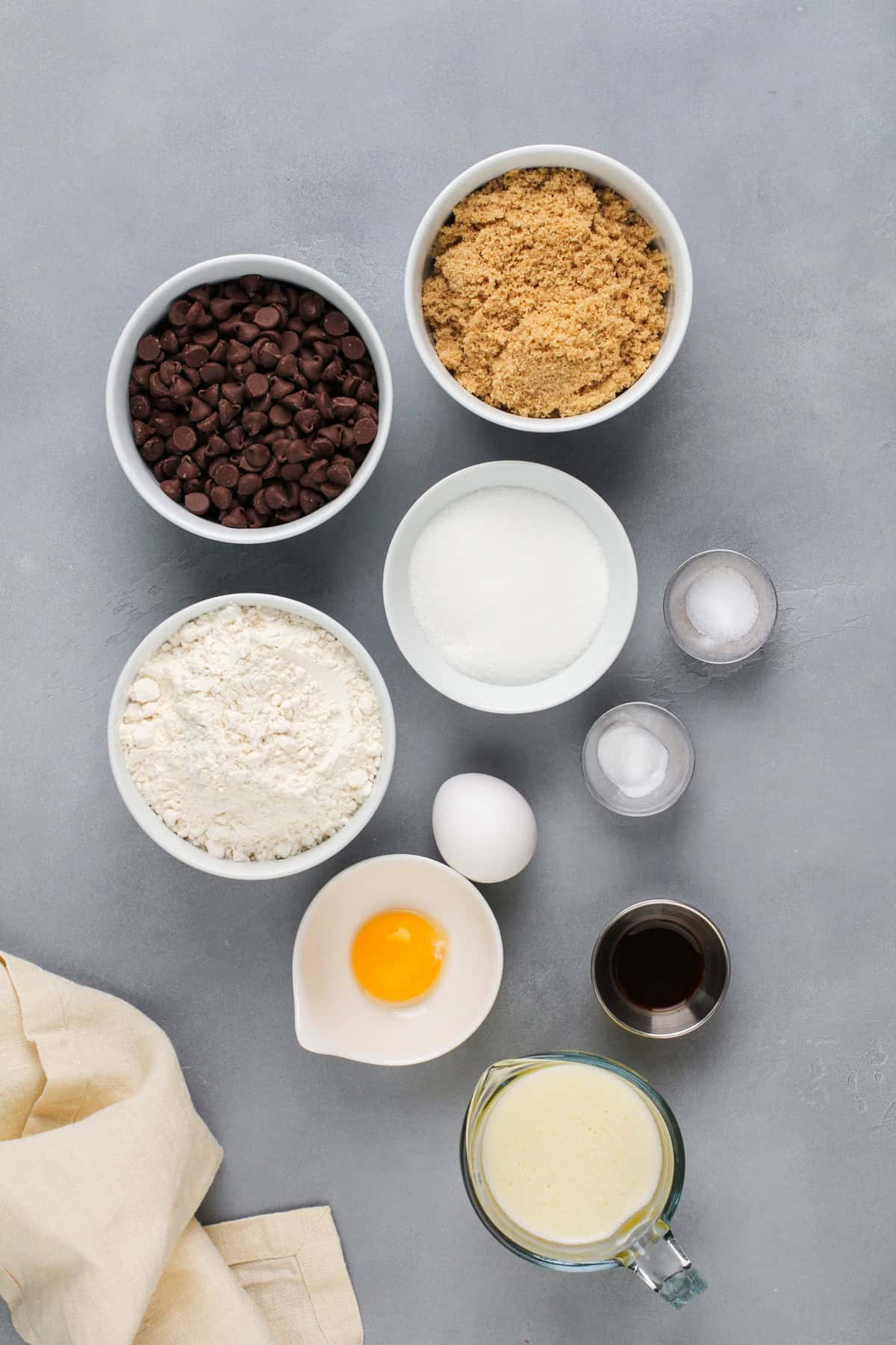 Ingredients for chocolate chip cookie bars arranged on a gray countertop.