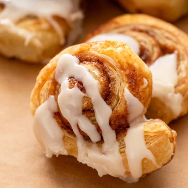 Close up of glazed puff pastry cinnamon roll.