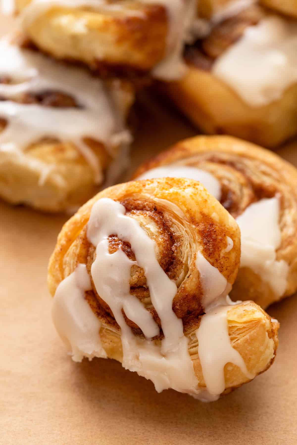 Close up of puff pastry cinnamon roll drizzled with powdered sugar glaze.