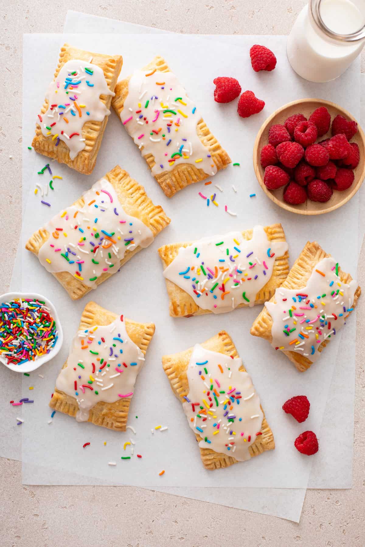 Frosted homemade pop tarts scattered on a piece of parchment paper.