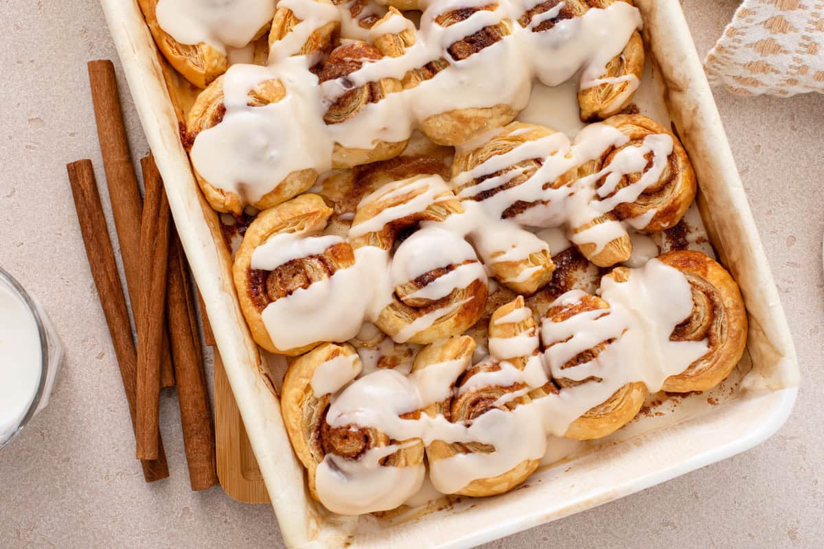 Overhead view of puff pastry cinnamon rolls in a white baking pan.