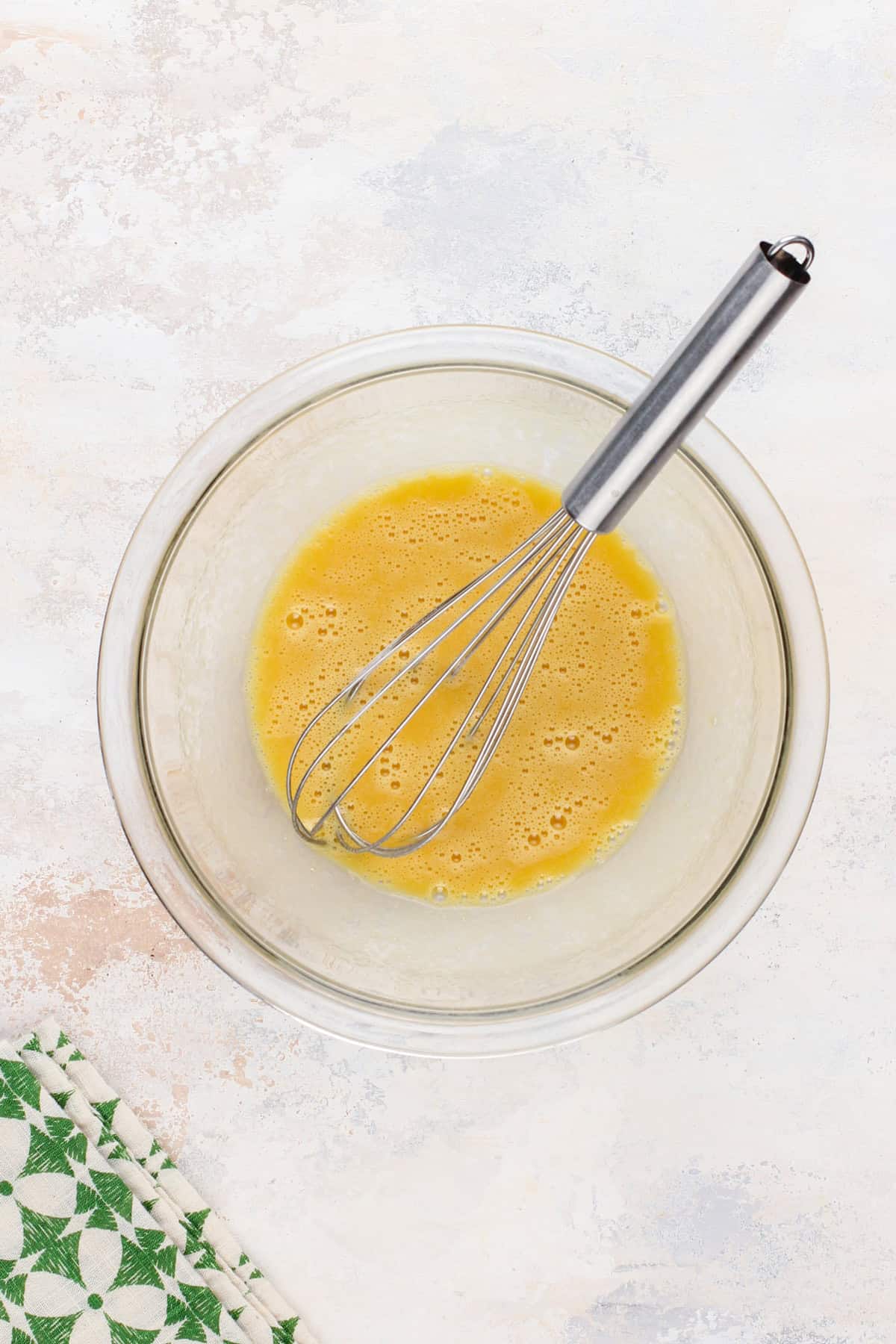 Wet ingredients for cake whisked together in a glass bowl.