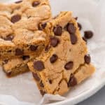 Chocolate chip cookie bar with a bite taken from the corner leaning against other cookie bars.