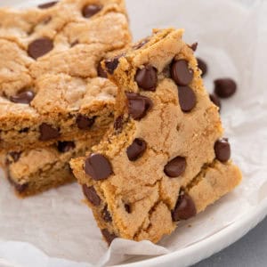 Chocolate chip cookie bar with a bite taken from the corner leaning against other cookie bars.