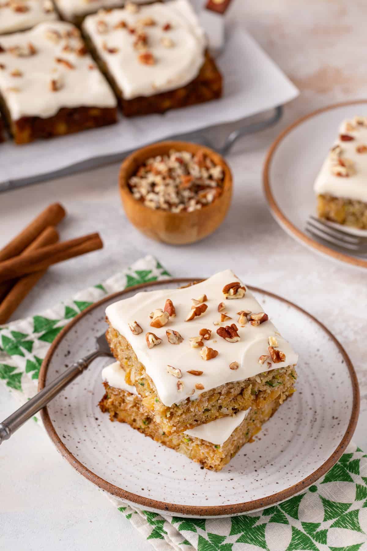 Two pieces of pineapple zucchini cake stacked on a plate.