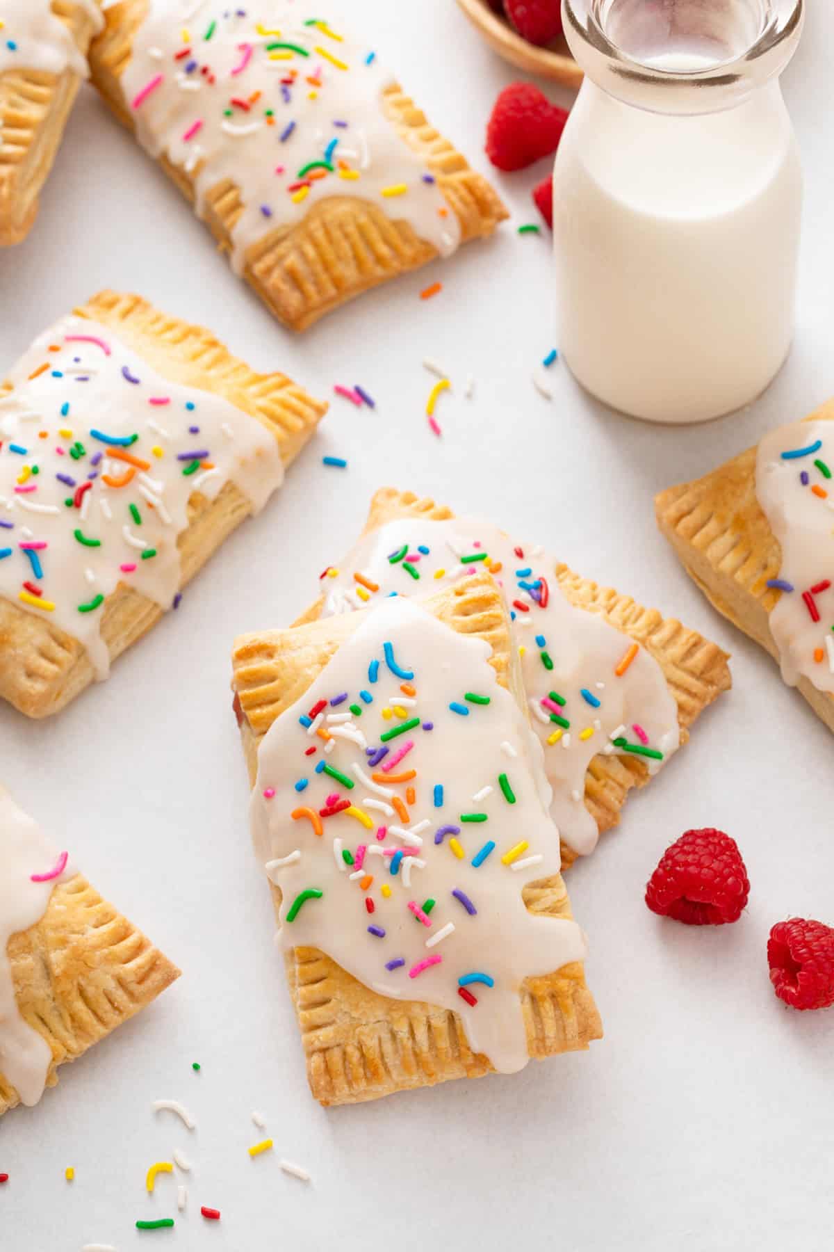 Frosted homemade pop tarts next to a glass of milk.