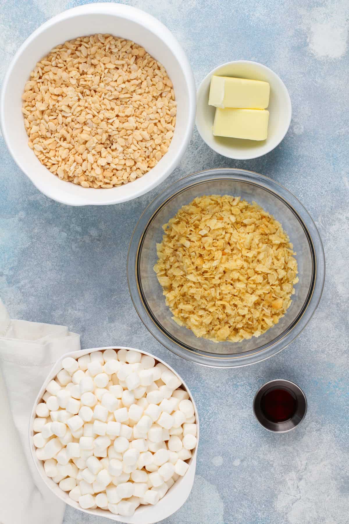 Ingredients for potato chip rice krispie treats on a blue countertop.